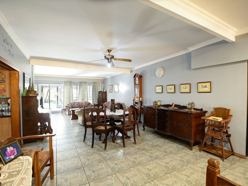 Spacious open-plan living and dining area featuring tiled flooring, crown molding, and large sliding glass doors leading to the outdoor space.