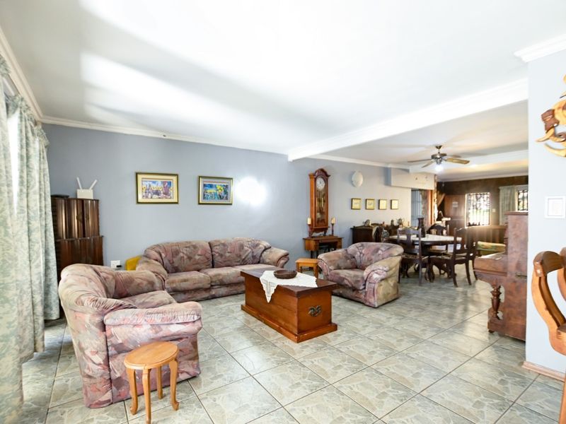 Spacious open-plan living and dining area featuring neutral wall tones, tiled flooring, and a ceiling fan, offering a versatile layout for family living.