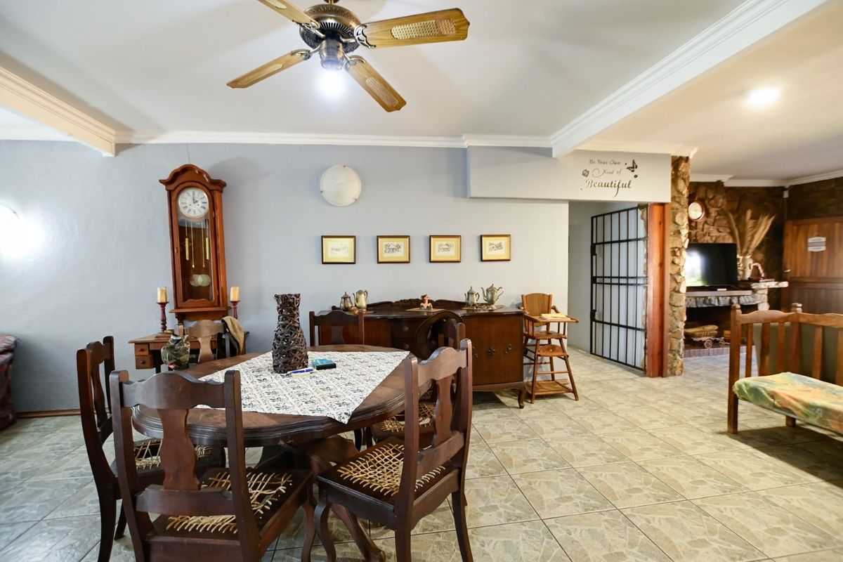 Spacious living area featuring tiled flooring, a ceiling fan, and a rustic stone fireplace, offering a warm and inviting atmosphere.