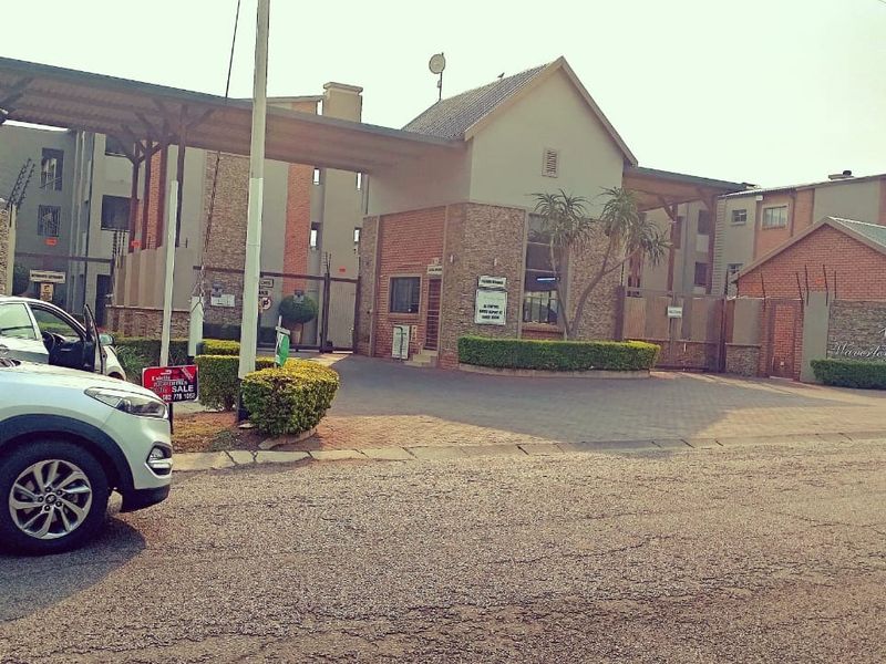 The main entrance and security gatehouse of the Waverley Square apartment complex, featuring brick construction and paved access.