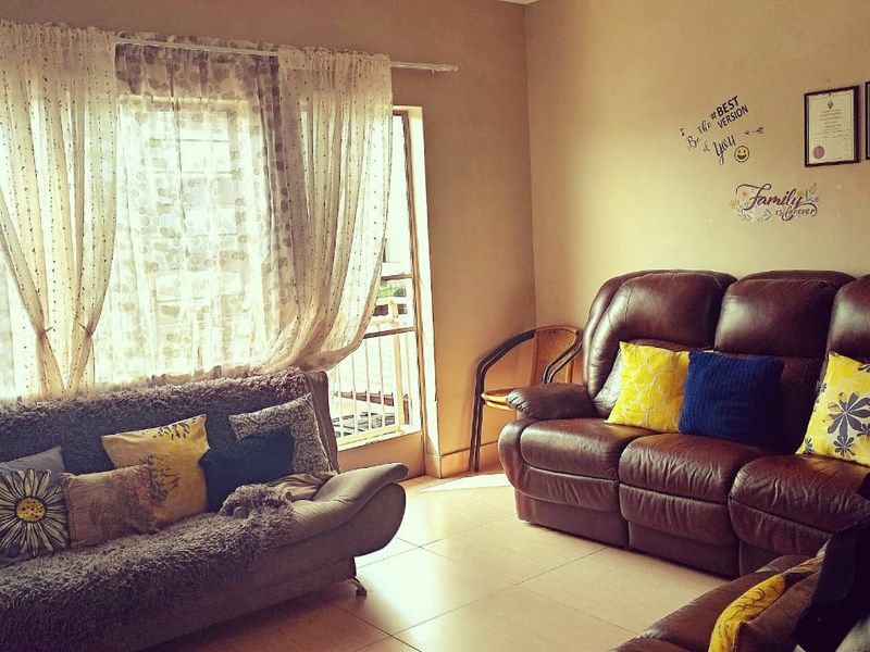 A comfortable living room featuring tiled flooring and direct access to a balcony through a sliding door.