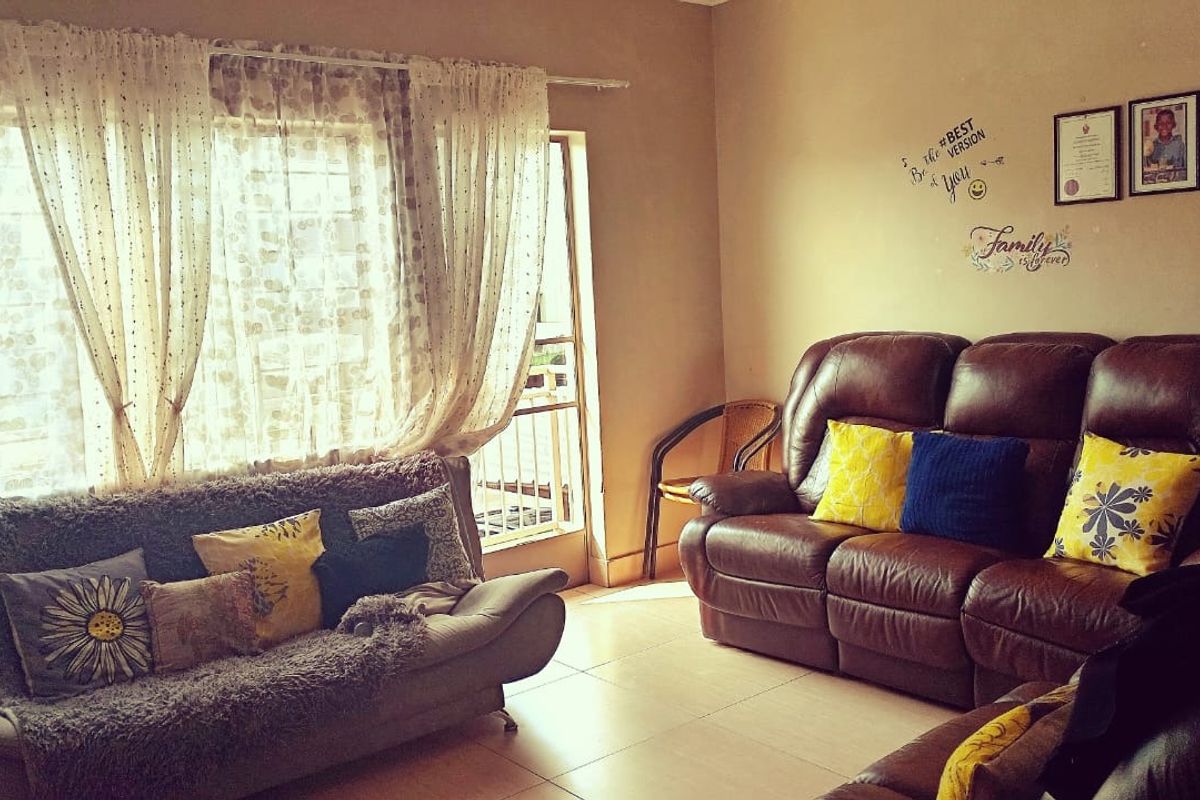 A comfortable living room featuring tiled flooring and direct access to a balcony through a sliding door.