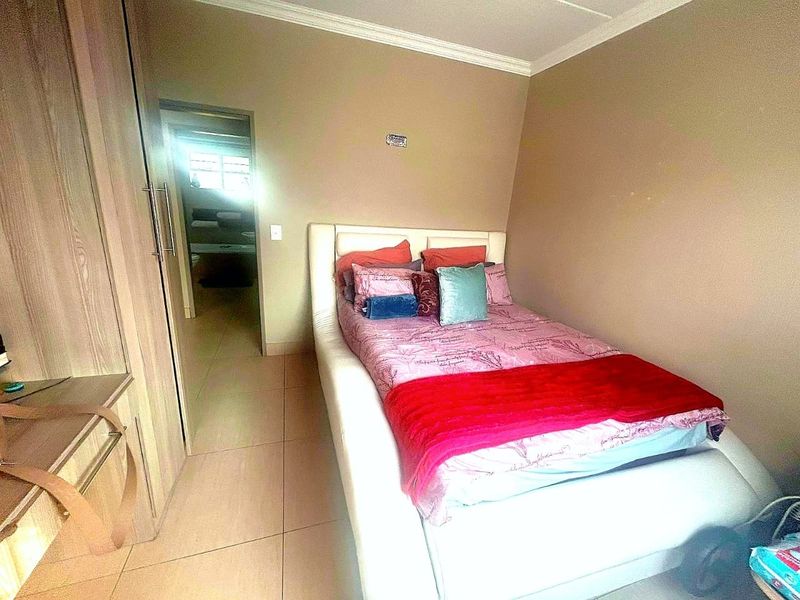 A compact bedroom featuring built-in cupboards and tiled flooring, with a doorway leading to an adjacent living area.