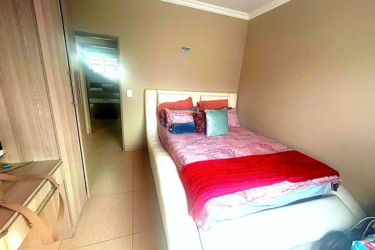 A compact bedroom featuring built-in cupboards and tiled flooring, with a doorway leading to an adjacent living area.