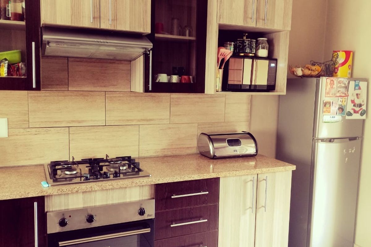 A functional kitchen featuring wood-finish cabinetry, granite countertops, a gas hob, and an integrated oven with a tiled backsplash.