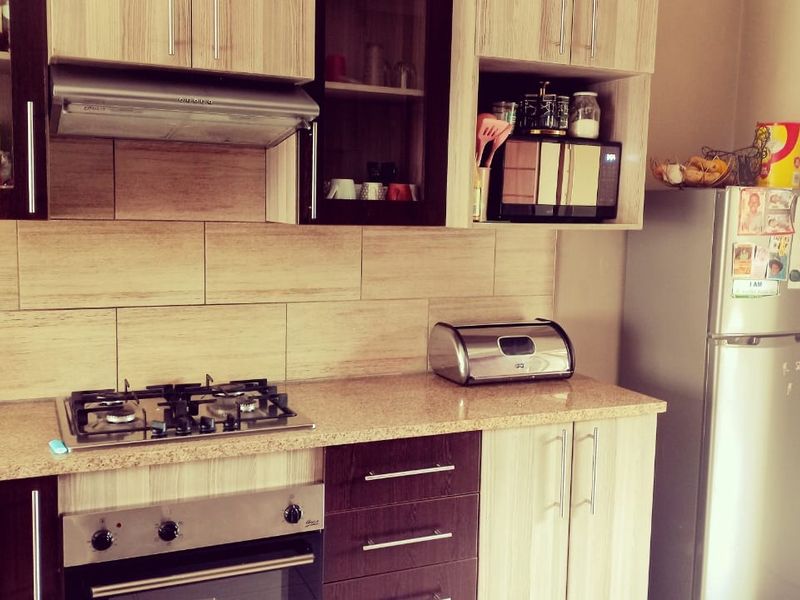A functional kitchen featuring wood-finish cabinetry, granite countertops, a gas hob, and an integrated oven with a tiled backsplash.