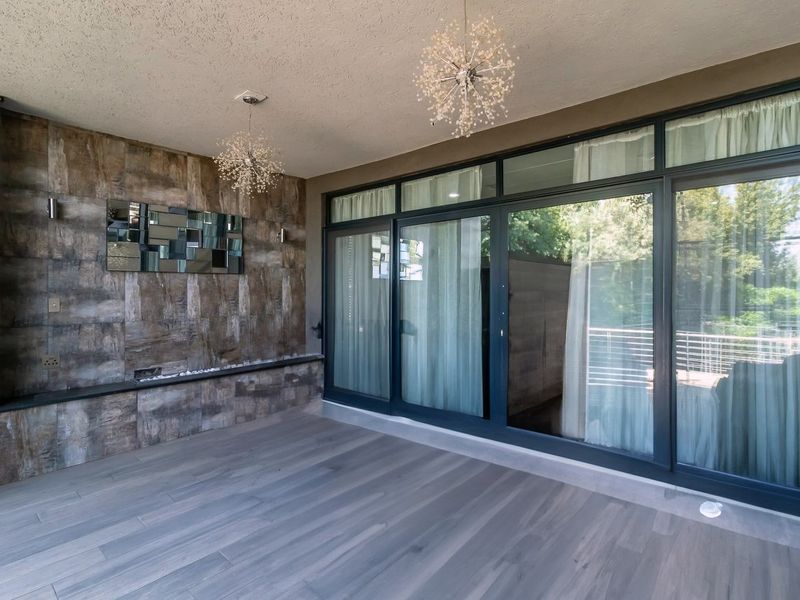 A modern covered patio featuring a textured tiled accent wall, built-in shelving, and expansive sliding glass doors that provide seamless indoor-outdoor flow.