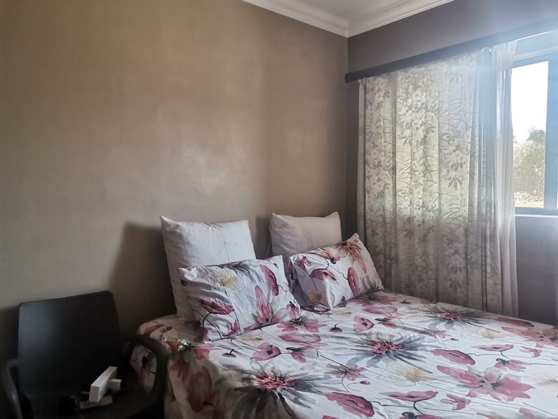A standard bedroom featuring neutral wall paint and a window with curtain fixtures.