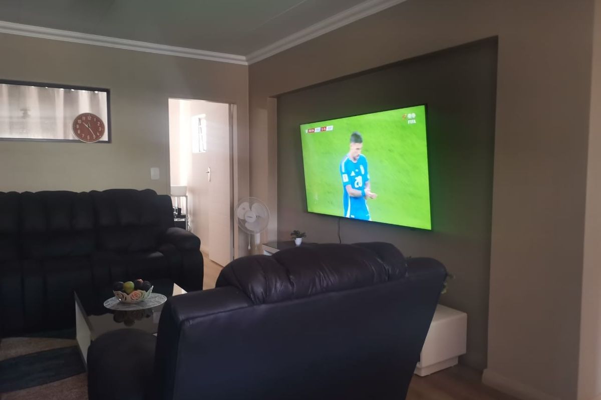 A comfortable living room featuring a recessed wall niche for media, coved ceiling cornicing, and durable laminate flooring.