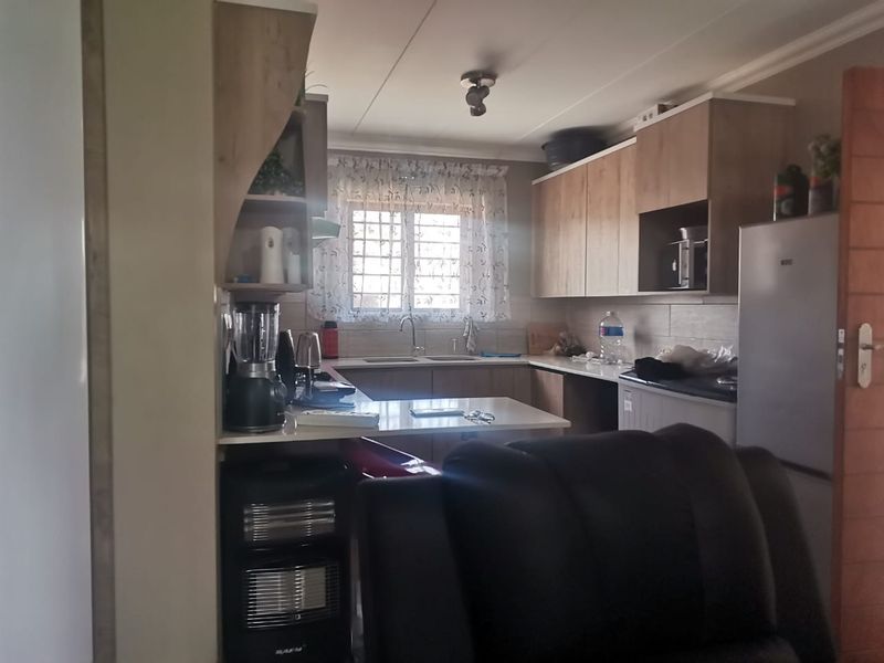 A functional kitchen featuring wood-look cabinetry, laminate countertops, a double sink, and tiled backsplash, offering a practical layout for daily meal preparation.