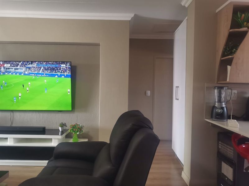 A comfortable living room featuring laminate flooring, cove cornicing, and a built-in wall niche for media equipment.
