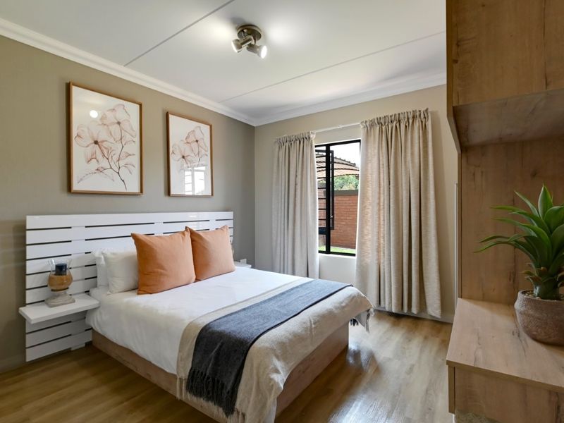 A well-maintained bedroom featuring laminate flooring, built-in cabinetry, and a custom headboard, offering a clean and functional living space.