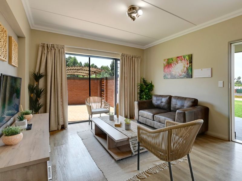 A well-maintained living room featuring laminate flooring, coved ceilings, and a sliding glass door providing direct access to an outdoor patio area.