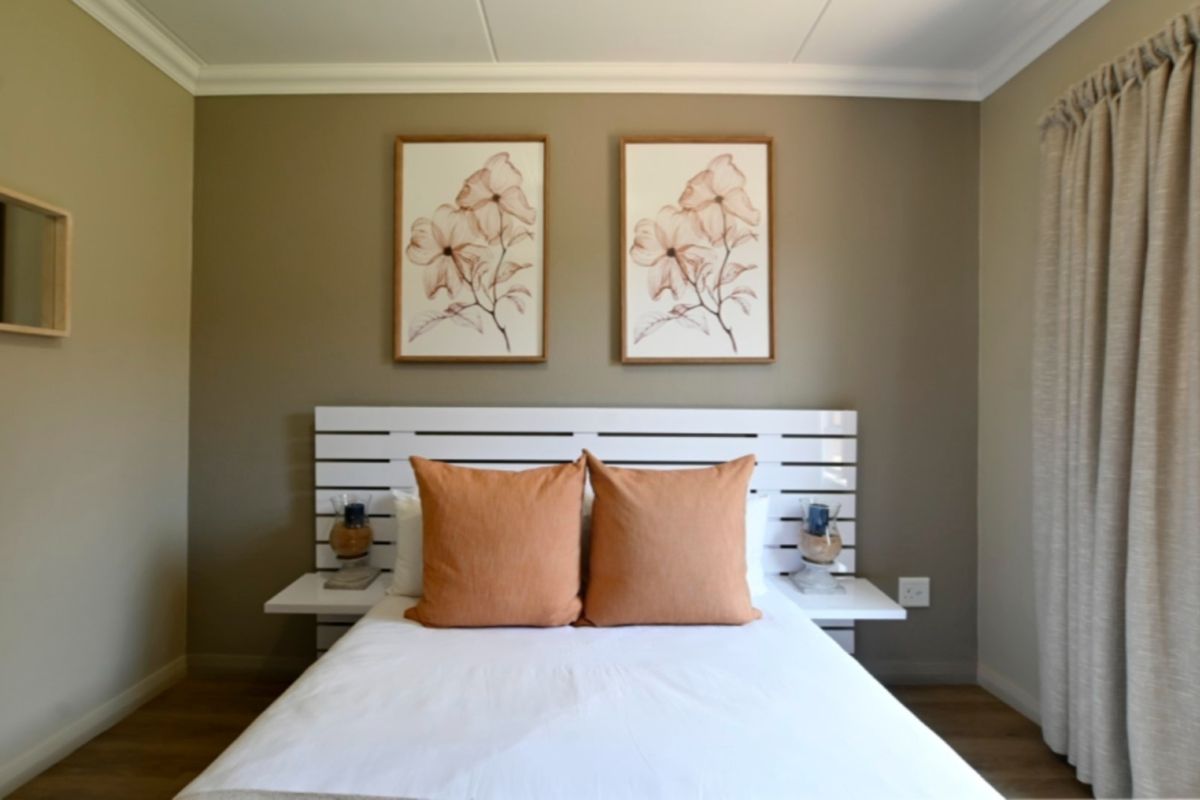A well-maintained bedroom featuring a built-in headboard with integrated bedside shelves, neutral wall tones, and laminate flooring.