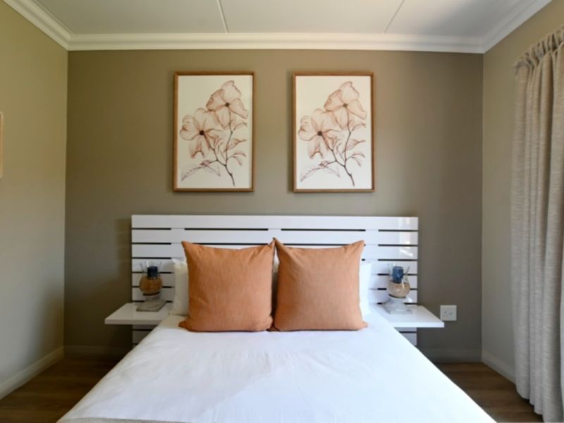A well-maintained bedroom featuring a built-in headboard with integrated bedside shelves, neutral wall tones, and laminate flooring.