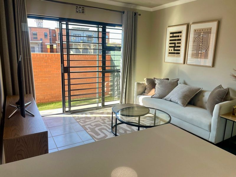 Open plan living area featuring tiled floors and a large sliding glass door with security gate providing access to the outdoor space.