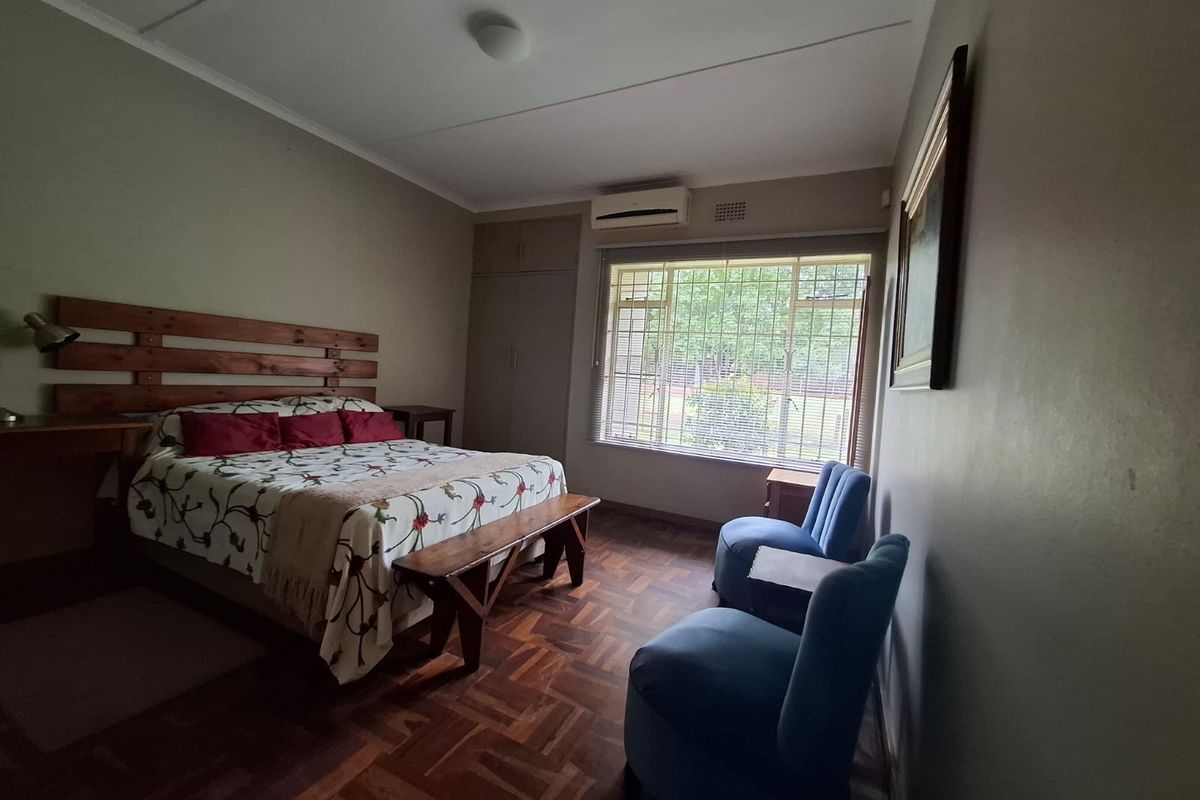 A well-proportioned bedroom featuring classic parquet flooring, built-in storage cupboards, and a wall-mounted air conditioning unit for climate control.