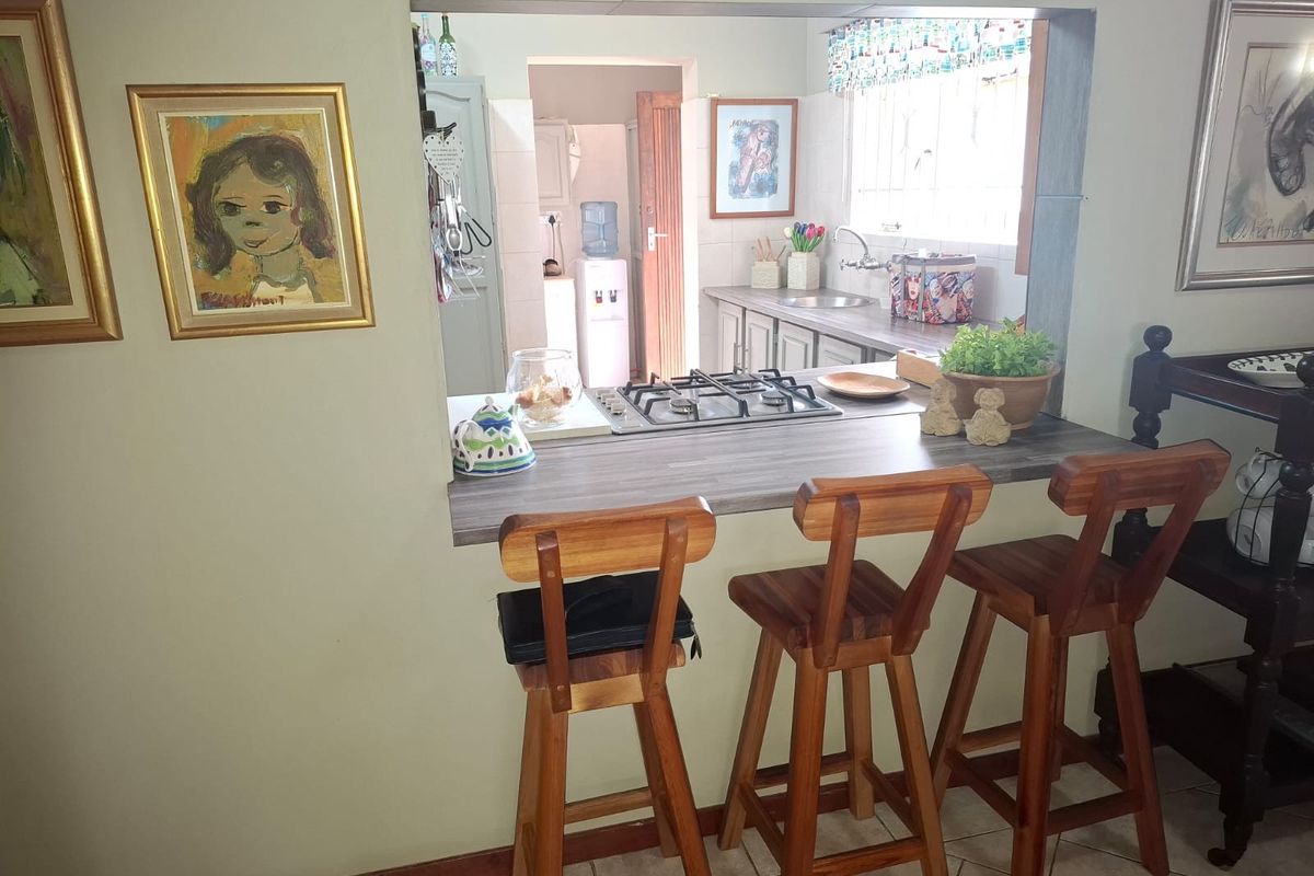 A functional kitchen featuring a gas hob, laminate breakfast bar, and sink, with a convenient pass-through window connecting to the adjacent living area.