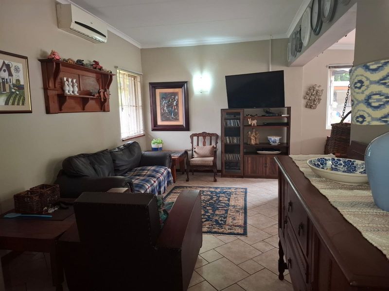 A comfortable living room featuring ceramic tile flooring, a wall-mounted air conditioning unit, and neutral wall finishes.