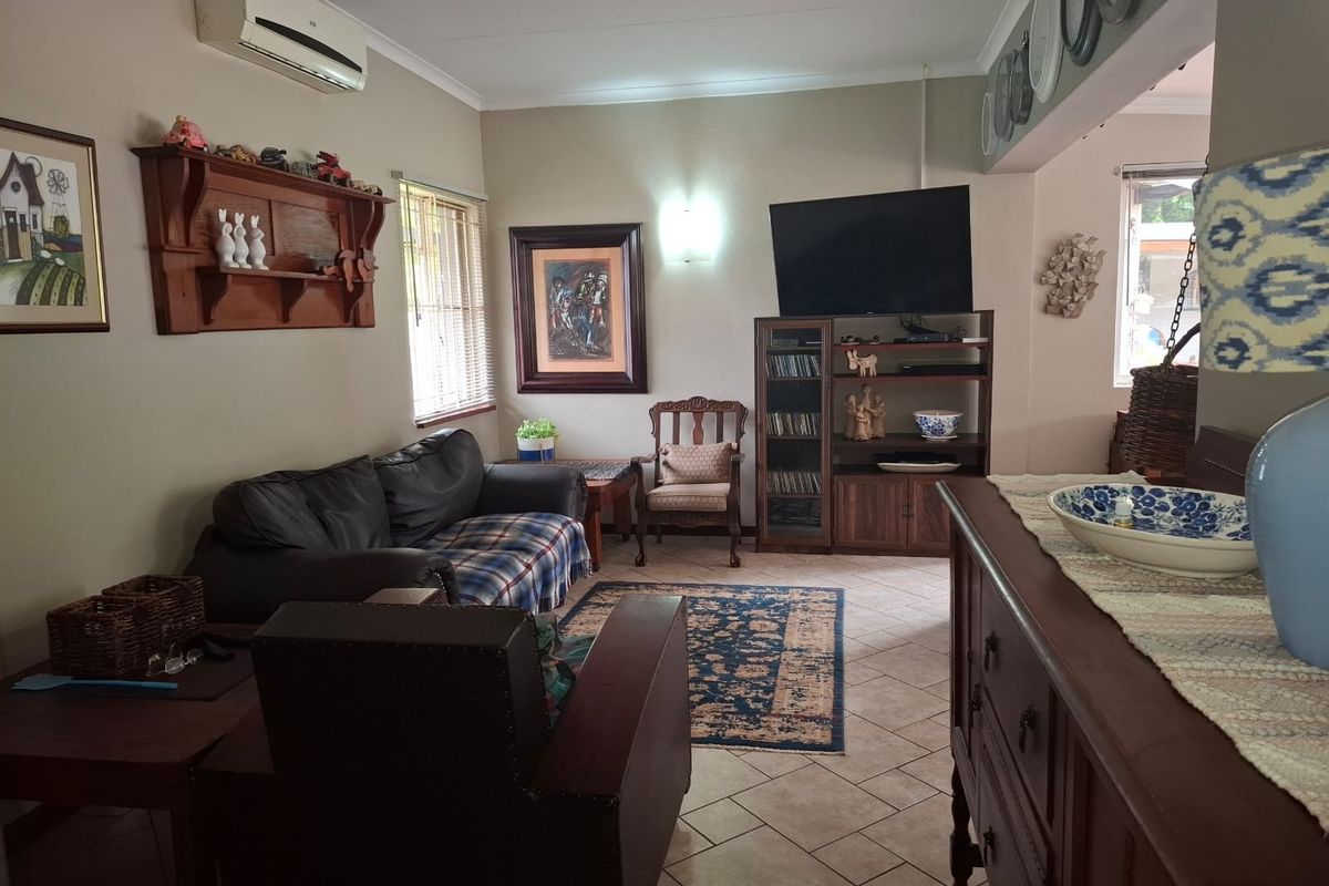 A comfortable living room featuring ceramic tile flooring, a wall-mounted air conditioning unit, and neutral wall finishes.
