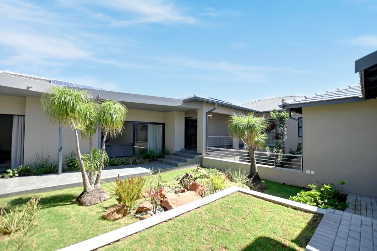 A well-maintained rear exterior view featuring a landscaped garden, paved walkways, and a covered patio area with modern architectural finishes.