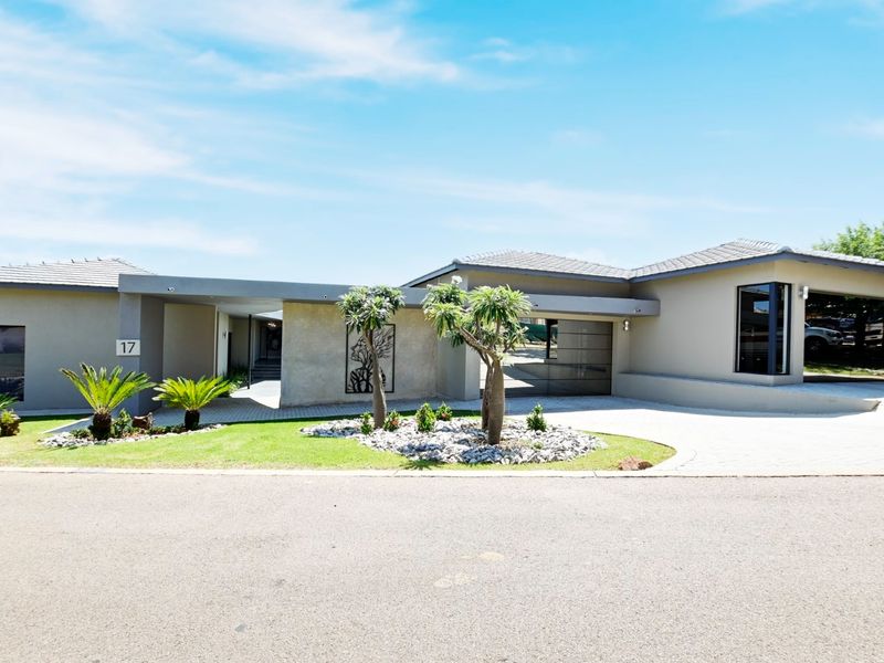 Modern single-story residence featuring a paved driveway, covered entrance, and well-maintained landscaped garden with a contemporary facade.