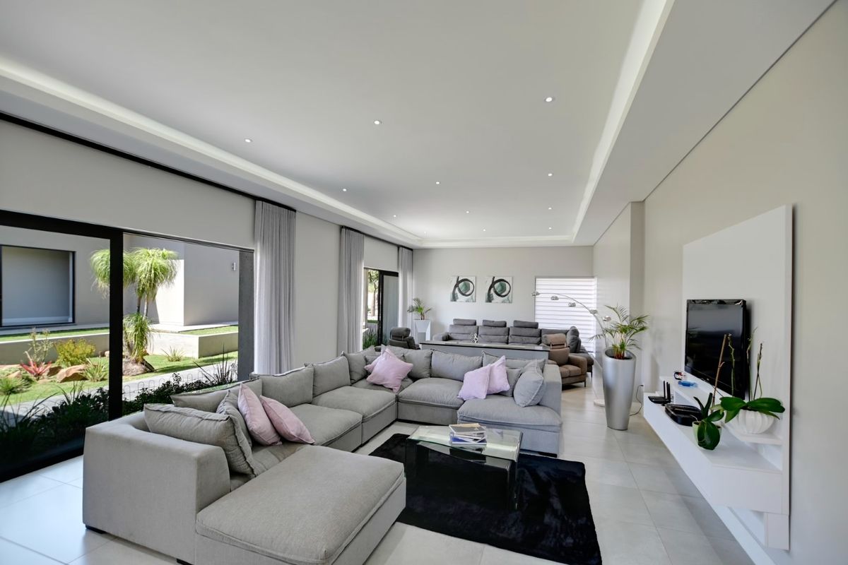 Spacious, modern living room featuring large sliding glass doors, recessed ceiling lighting, cove lighting, and a sleek built-in media console.