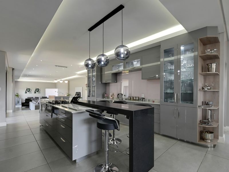Modern open-plan kitchen featuring a large island with a gas hob, breakfast bar, sleek cabinetry, and elegant recessed lighting.