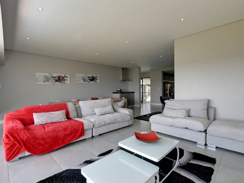 Spacious open-plan living and dining area featuring modern tiled flooring, recessed downlighting, and a sleek kitchen prep area with built-in cabinetry.