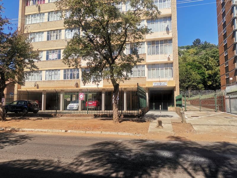 Front elevation of Tuscaloosa Flats apartment building featuring brick facade, secure gated parking area, and street-level access.