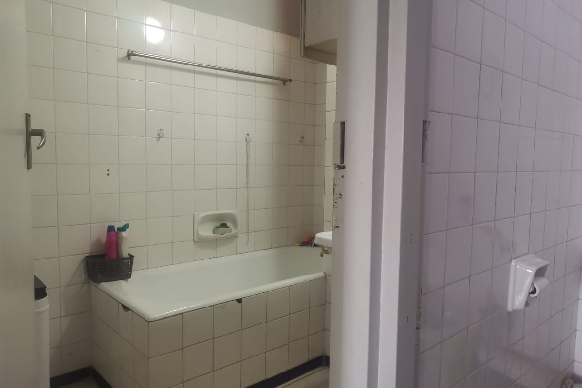 A functional bathroom featuring a standard bathtub, fully tiled walls, and basic fixtures, presenting an opportunity for modernization and cosmetic updates.