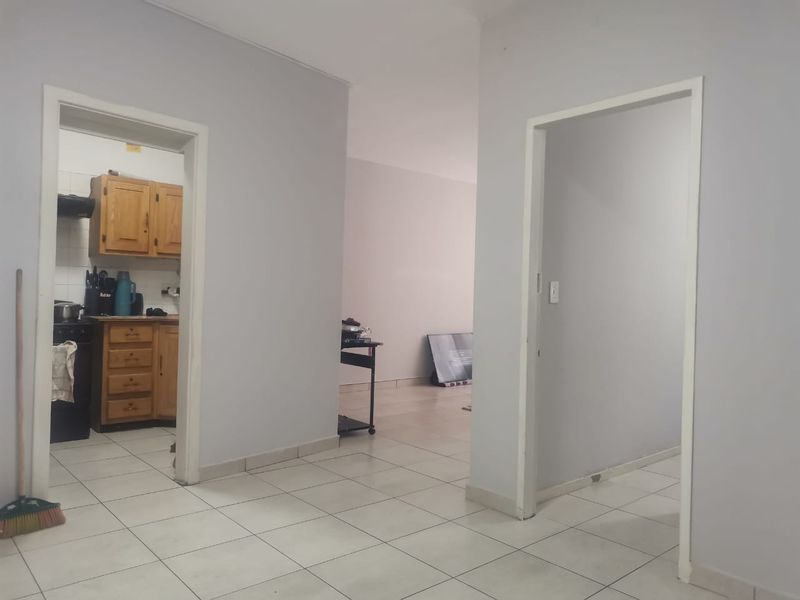 A view from the hallway looking into the kitchen and adjacent living area, featuring neutral wall tones and tiled flooring throughout.