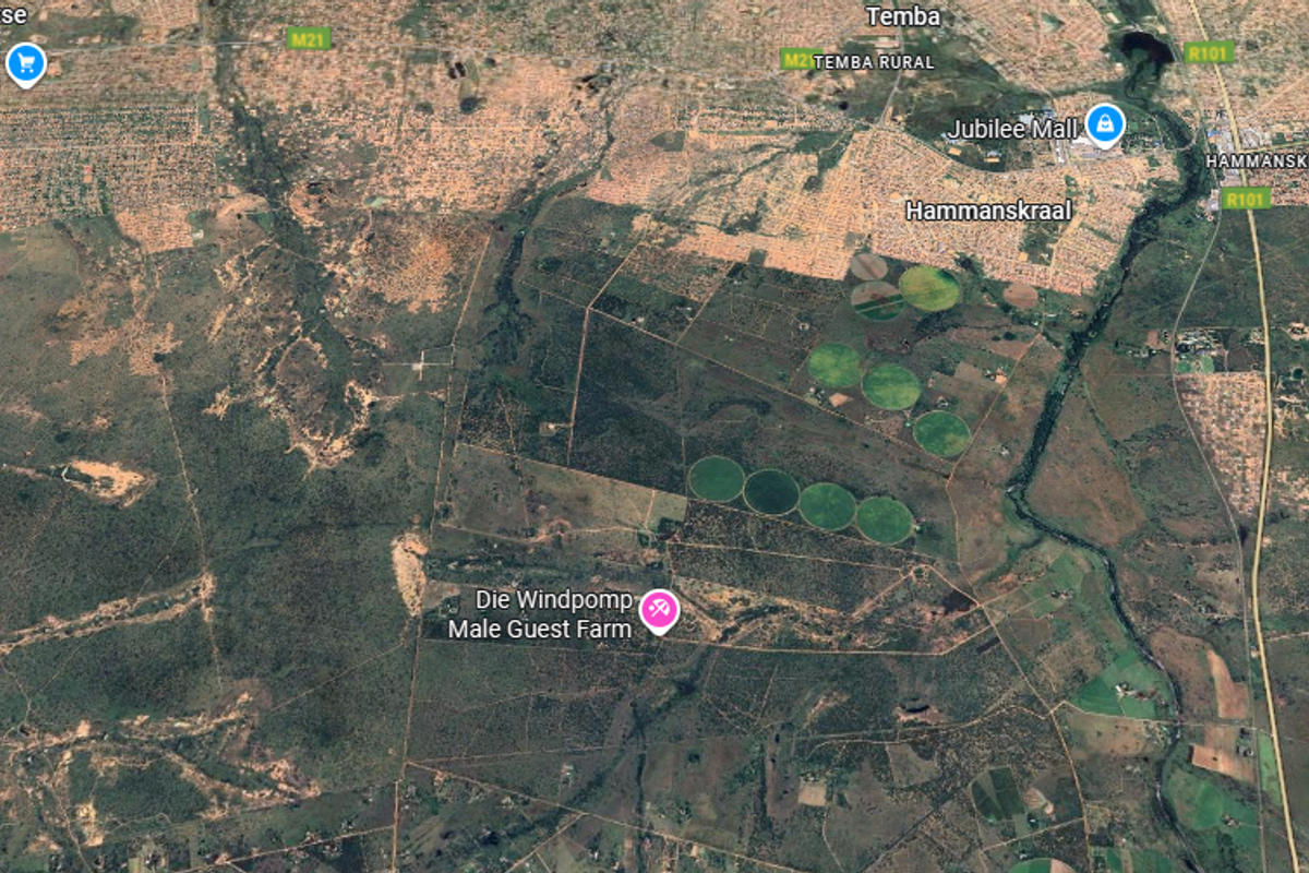 An aerial satellite view showing the farm property layout, surrounding landscape, irrigation circles, and proximity to local infrastructure and main roads.