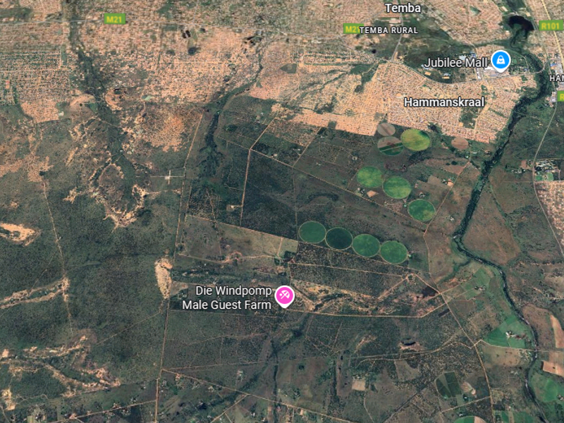 An aerial satellite view showing the farm property layout, surrounding landscape, irrigation circles, and proximity to local infrastructure and main roads.