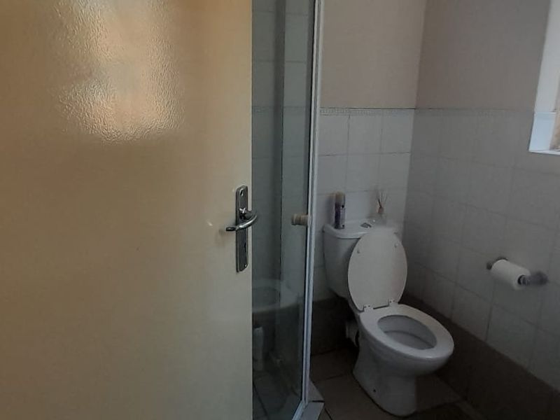 A functional bathroom featuring a shower enclosure, pedestal basin, and toilet with tiled wall finishes.