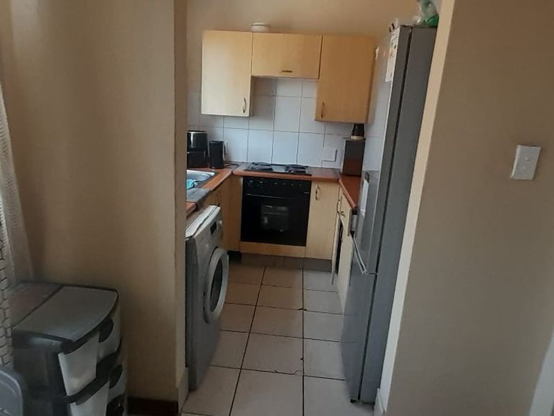 Compact kitchen featuring built-in cabinetry, tiled flooring, and integrated cooking appliances, offering a functional layout for an apartment setting.