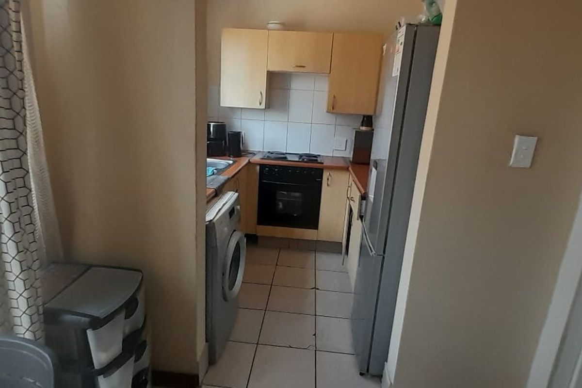 Compact kitchen featuring built-in cabinetry, tiled flooring, and integrated cooking appliances, offering a functional layout for an apartment setting.