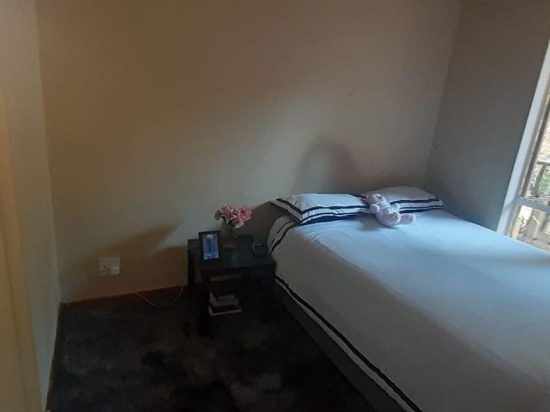 A bedroom featuring a large window and an en-suite bathroom with a pedestal basin.
