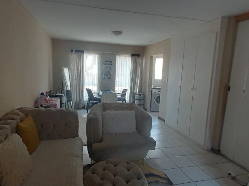 Open plan living area featuring tiled flooring and built-in storage cupboards, with direct access to an outdoor balcony area.