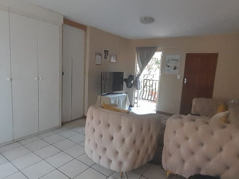 A living room featuring tiled flooring and built-in cupboards, with direct access to an outdoor balcony area.