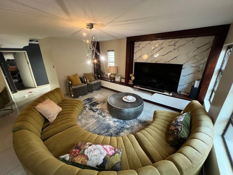 A contemporary living room featuring a custom built-in media unit with a marble-look feature wall and modern lighting fixtures.