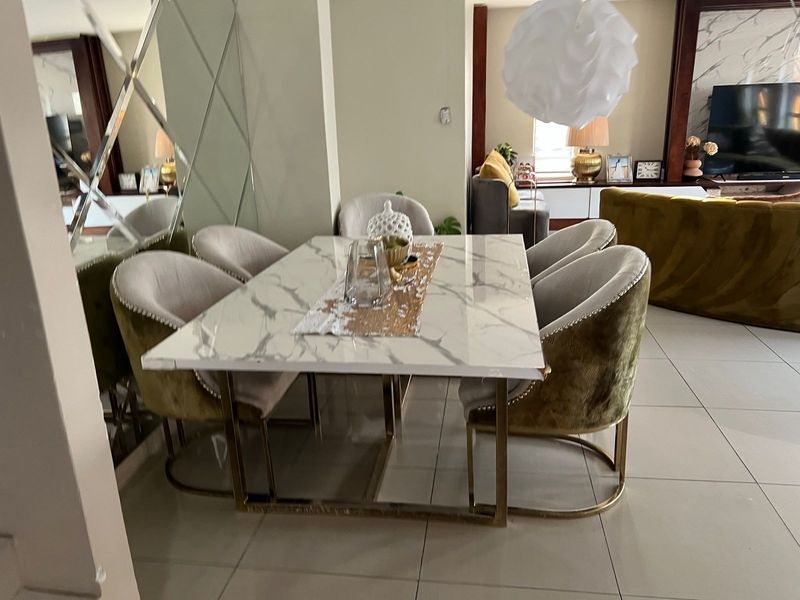 A well-lit dining area featuring large format floor tiles and a decorative mirrored wall feature, seamlessly connected to the adjacent living space.