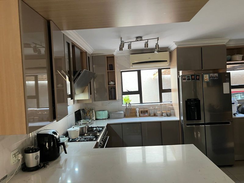 Modern kitchen featuring sleek cabinetry, stone countertops, a gas hob with extractor fan, and an integrated air conditioning unit for climate control.