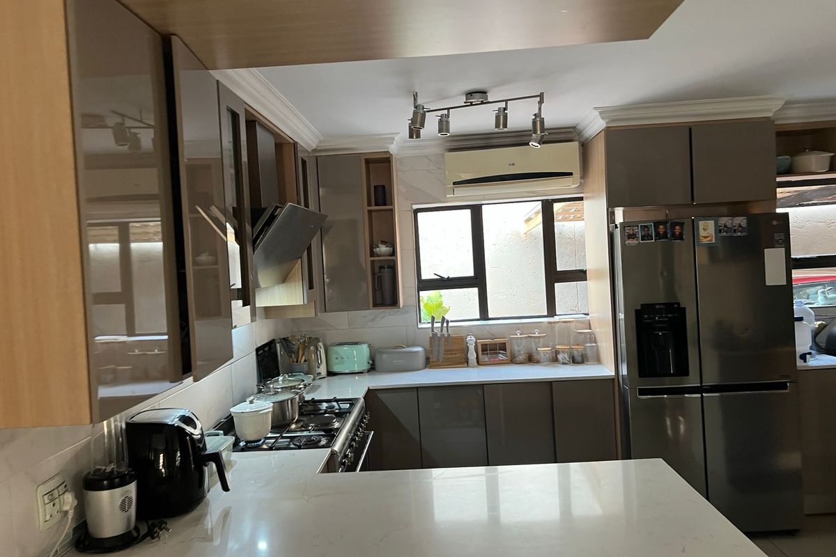Modern kitchen featuring sleek cabinetry, stone countertops, a gas hob with extractor fan, and an integrated air conditioning unit for climate control.