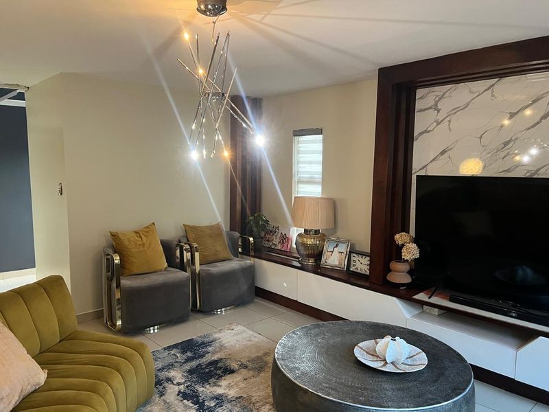 A contemporary living room featuring a built-in media console with marble-look accents, tiled flooring, and a stylish modern pendant light fixture.