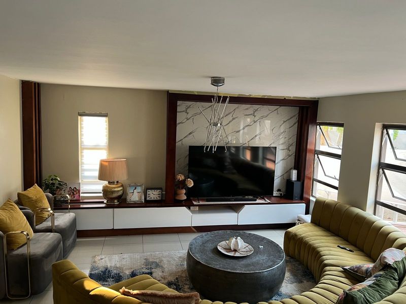 A comfortable living room featuring a custom built-in media unit with a marble-look accent wall and tiled flooring.
