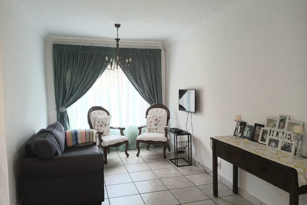 A well-lit living room featuring neutral tiled flooring and coved ceilings, providing a clean and functional space for relaxation.