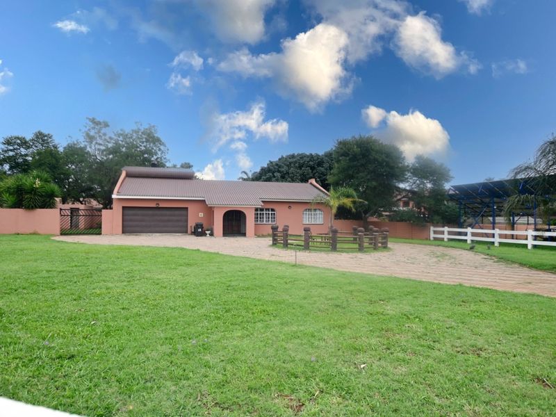Front view of a single-story farm property featuring a paved driveway, attached garage, and well-maintained lawn area.