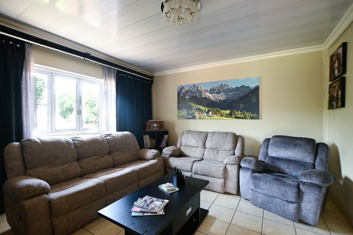 A comfortable living room featuring tiled flooring, a PVC ceiling, and a large window providing natural light.