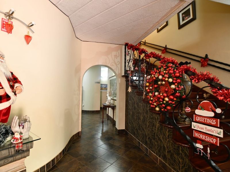 A welcoming hallway featuring a decorative wrought iron staircase railing, tiled flooring, and an arched entryway leading to adjacent living spaces.